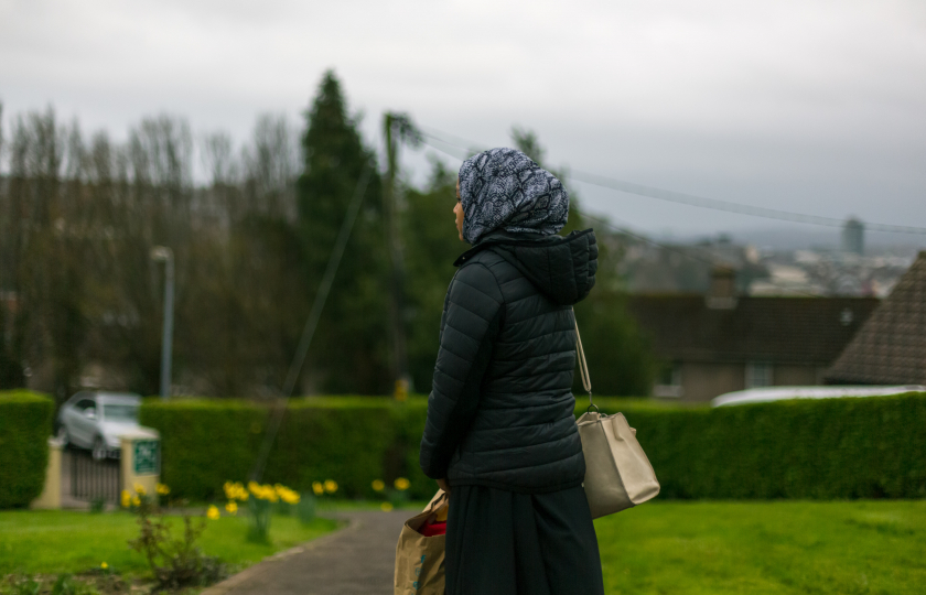 Young woman standing in a green area with her faced turned away from the camer